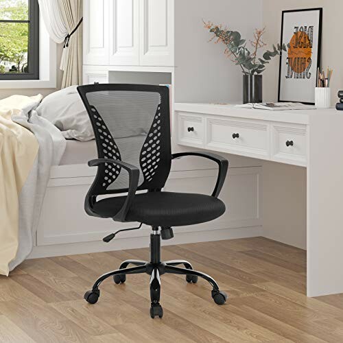 Chaise de bureau noire devant un bureau blanc dans une chambre.
